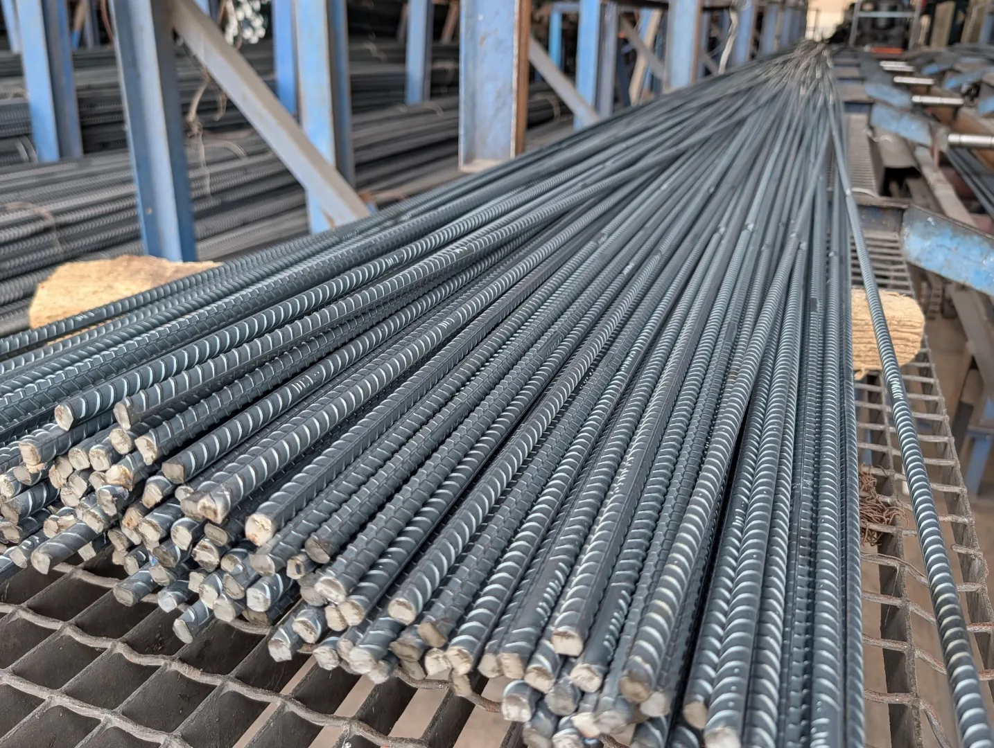 Straight reinforcement bars laid on the feed table, ready to be cut and bent to a bar bending schedule